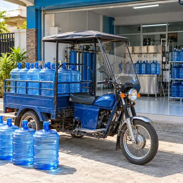 Clean refillable water containers and a delivery tricycle at a refilling shop